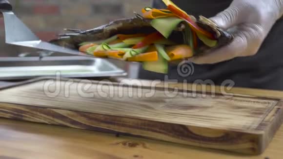 厨师把烤鱼放在木板上用蔬菜装饰木制烤鱼和新鲜蔬菜视频的预览图