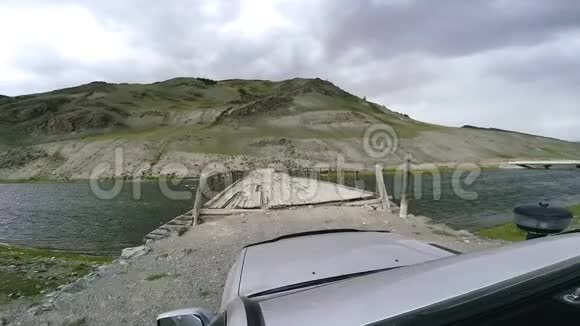 汽车旅行SUV骑在高山公路上的老木桥上在道路上行驶的汽车的视角视频的预览图