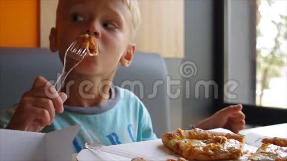 可爱有趣的男孩在快餐店吃比萨饼胃口很好视频的预览图