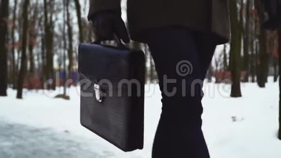 面目全非的商人或律师穿着正式西装公文包走在白雪覆盖的冬季公园里视频的预览图