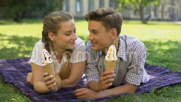 青少年躺在公园的格子呢里在户外吃冰淇淋浪漫的约会视频的预览图