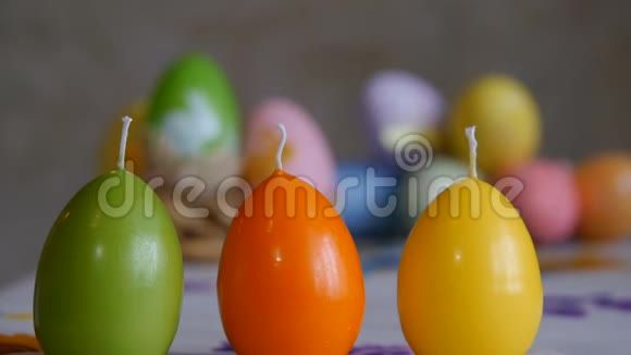 用复活节彩蛋做成的蜡烛绿色橙色黄色女性手点燃蜡烛视频的预览图