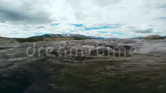 晶莹剔透的饮用水在山河小溪中流淌冰冷的河水顺着鹅卵石和岩石流下来视频的预览图