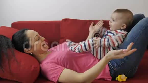 小妈妈在沙发上拍着小儿子手视频的预览图