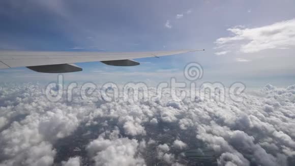 飞机高高地飞在云层和地面上天空蓝天中的飞机翼视频的预览图