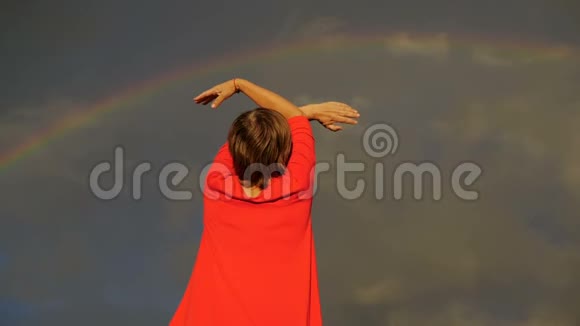 在彩虹天气里举起双手飞向天空的女人的后镜头视频的预览图