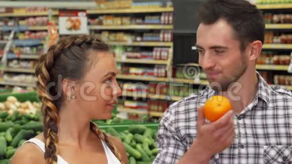 快乐的年轻夫妇在买食物的时候闻着橘子视频的预览图