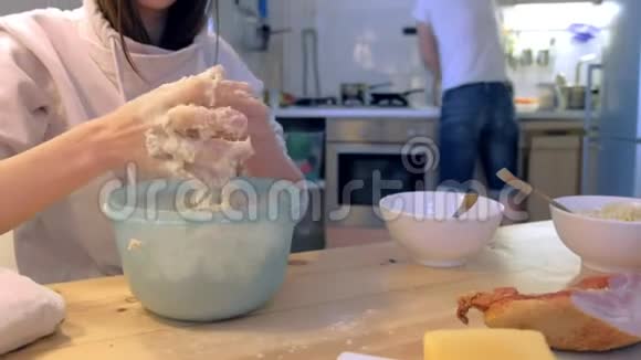 家人正在做披萨女人把披萨面团揉在碗里双手特写视频的预览图