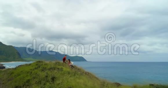 一对夫妇坐在靠近海岸的青山上视频的预览图