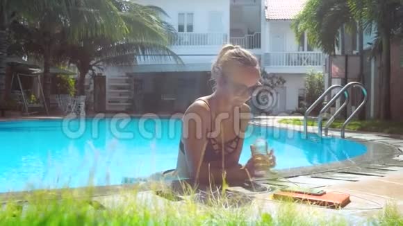 女孩拿着水瓶和饮料靠在泳池屏障上视频的预览图