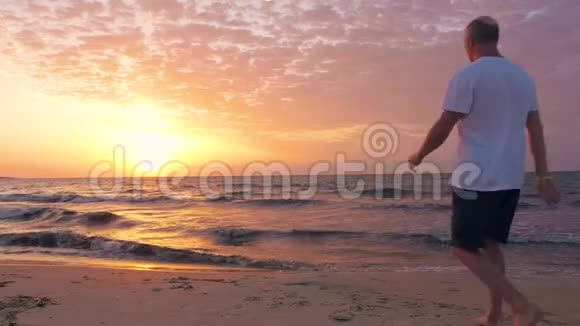 中年男子迎着美丽的日出登上海滨迎接太阳视频的预览图