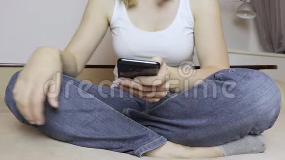 女人盘腿坐在沙发上用智能手机视频的预览图