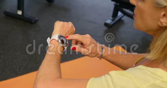 4k健身室的高级妇女检查她的智能手表视频的预览图