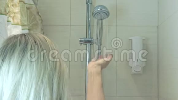 金发女人在浴室里从淋浴头上往下掉身体护理概念视频的预览图