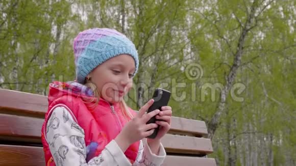春城公园坐在长椅上玩智能手机的青少年女孩视频的预览图