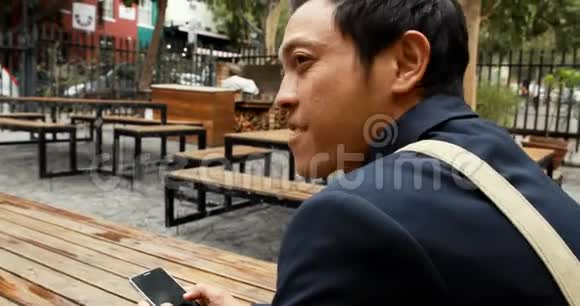 商务人士坐在户外咖啡馆的长椅上视频的预览图
