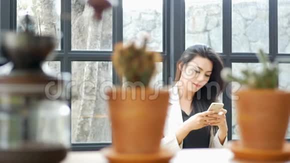 美丽的亚洲年轻商务女性穿着西装外套在智能手机上应用在现代办公室与朋友发短信聊天视频的预览图