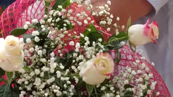 花作为节日的礼物特写镜头鲜花和红玫瑰在男人手中特写镜头视频的预览图