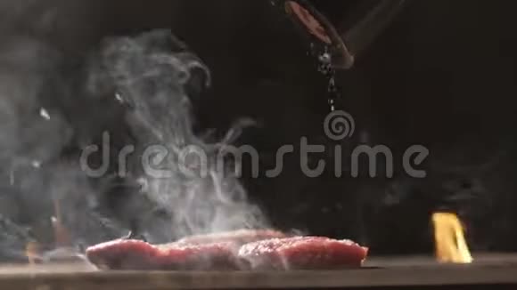 烤肉牛排生火做饭慢动作牛肉牛排特写厨师用香料和胡椒洒肉视频的预览图