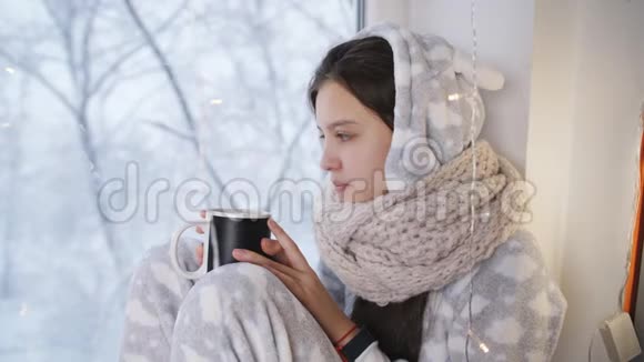 病女少年冬穿着睡衣坐在窗前和越热茶视频的预览图