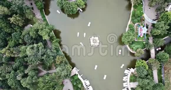 人们在城市公园放松围绕着绿色喷泉池塘和船只漂浮视频的预览图