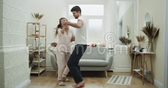 快乐的一对夫妇穿着睡衣在他们舒适的客厅里跳舞视频的预览图