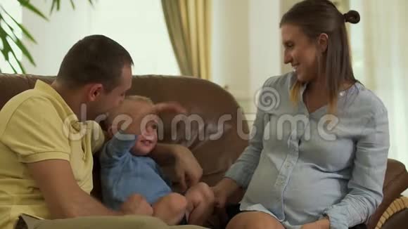 年轻的父母和小儿子一起躺在沙发上视频的预览图