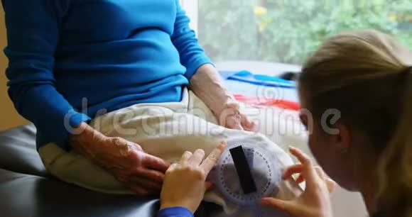理疗师用4k测角仪检查老年妇女膝盖视频的预览图