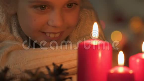 兴奋的女孩看着燃烧的蜡烛在圣诞节许愿特写视频的预览图