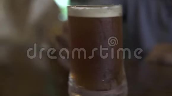 朋友们在酒吧里喝着啤酒杯人们拿着冰冷的啤酒杯在酒吧柜台一起喝酒视频的预览图