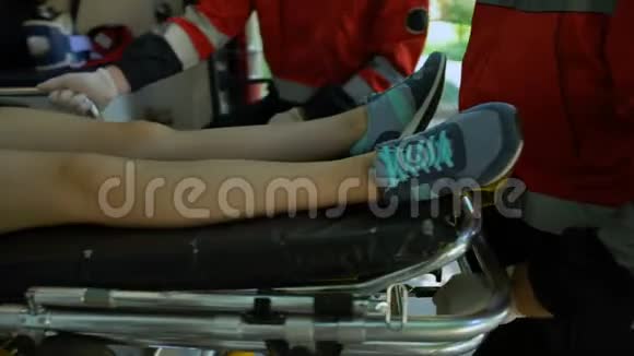 医护人员将担架上的妇女抬上救护车组成合格的救援队视频的预览图