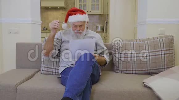 圣诞老人的帽子上戴着的老人读着圣诞老人的家庭愿望清单视频的预览图