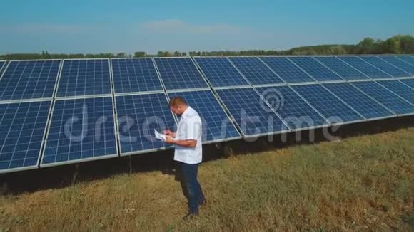 在草地上的太阳能发电站工作的人无人机射击视频的预览图