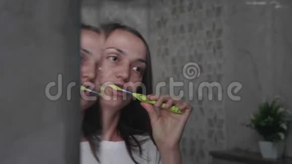 年轻女子正在浴室里用牙刷刷牙视频的预览图