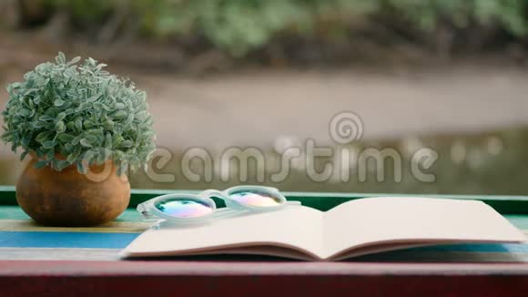 4K木桌上放着花盆放在闪闪发光的河底上的空白书的电影片视频的预览图
