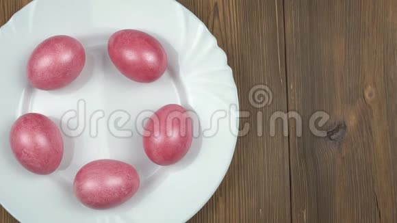 男性手在盘子里放一个绿色的复活节彩蛋背景是红色的珍珠蛋母盘木制视频的预览图