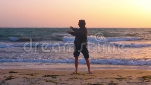 健身男子在傍晚海滩和海浪景观上做热身运动视频的预览图