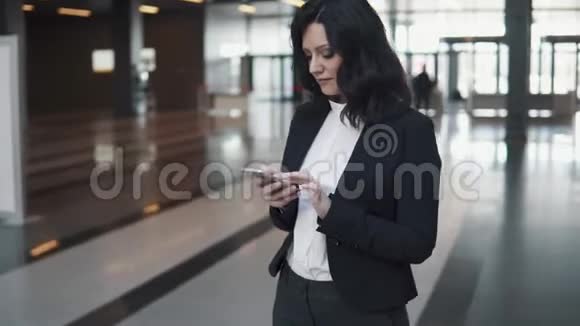 一个女商人手里拿着电话的肖像办公楼大厅里的年轻女子视频的预览图