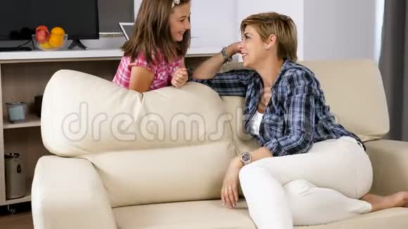 妈妈带着十几岁的女儿在客厅里笑着玩视频的预览图