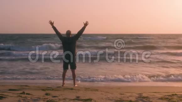 站在海岸海浪和天空背景上的人伸出双臂视频的预览图