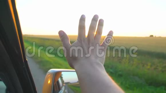日落时分的人手一个人在阳光下从车窗手在大自然的背景景观上看到阳光荣耀视频的预览图