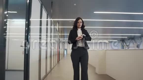 自信的商务女性使用手机穿着西装的女孩穿过办公楼视频的预览图
