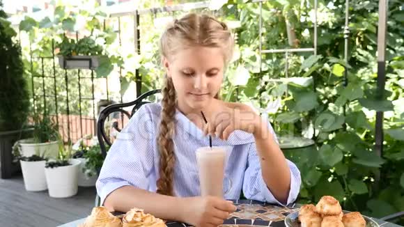 咖啡店的概念街头咖啡馆里小女孩在外面吃饭的肖像她喝了一口后笑了视频的预览图