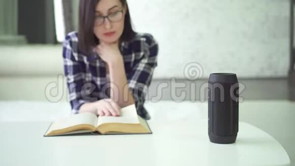 带眼镜的漂亮女孩在看书时使用语音助手视频的预览图
