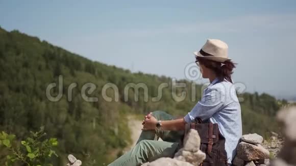 女旅行者坐在悬崖边休息山里的徒步旅行者视频的预览图