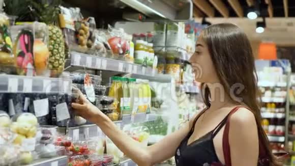成人年轻美丽的女人模特在食品店选择新鲜浆果饮食4K视频的预览图