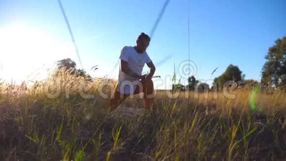 阳光明媚的一天年轻人在草地上做运动运动男在球场上练习瑜伽夏季景观视频的预览图