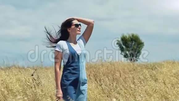 美丽的年轻女子站在麦地或干草地享受着壮丽的大自然视频的预览图