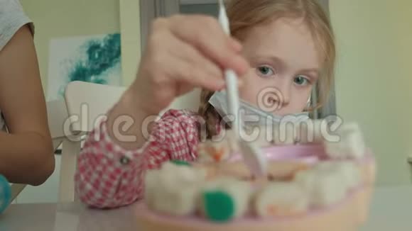 一个年轻的女人和一个女孩用塑料制成牙齿把牙齿插入玩具的下巴女孩做了一个视频的预览图