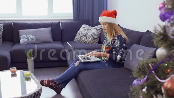 戴着圣诞帽子的漂亮女孩通过网络购物视频的预览图